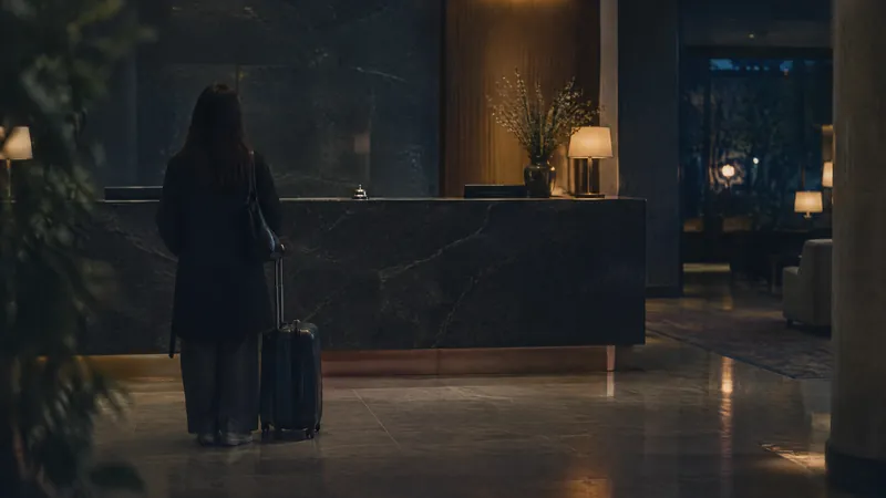 Guest with a suitcase waiting at a dark stone hotel reception desk