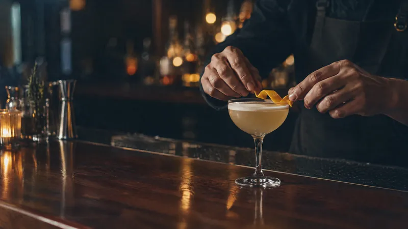 Bartender finishing a cocktail with a citrus twist at a dim bar