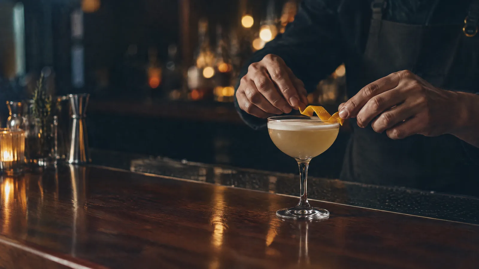 Bartender finishing a cocktail with a citrus twist at a dim bar
