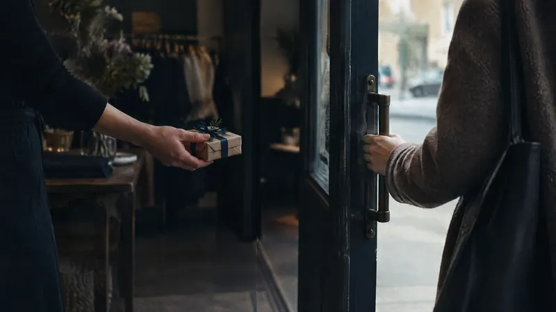 Hand passing a small parcel through a shop doorway to a waiting customer