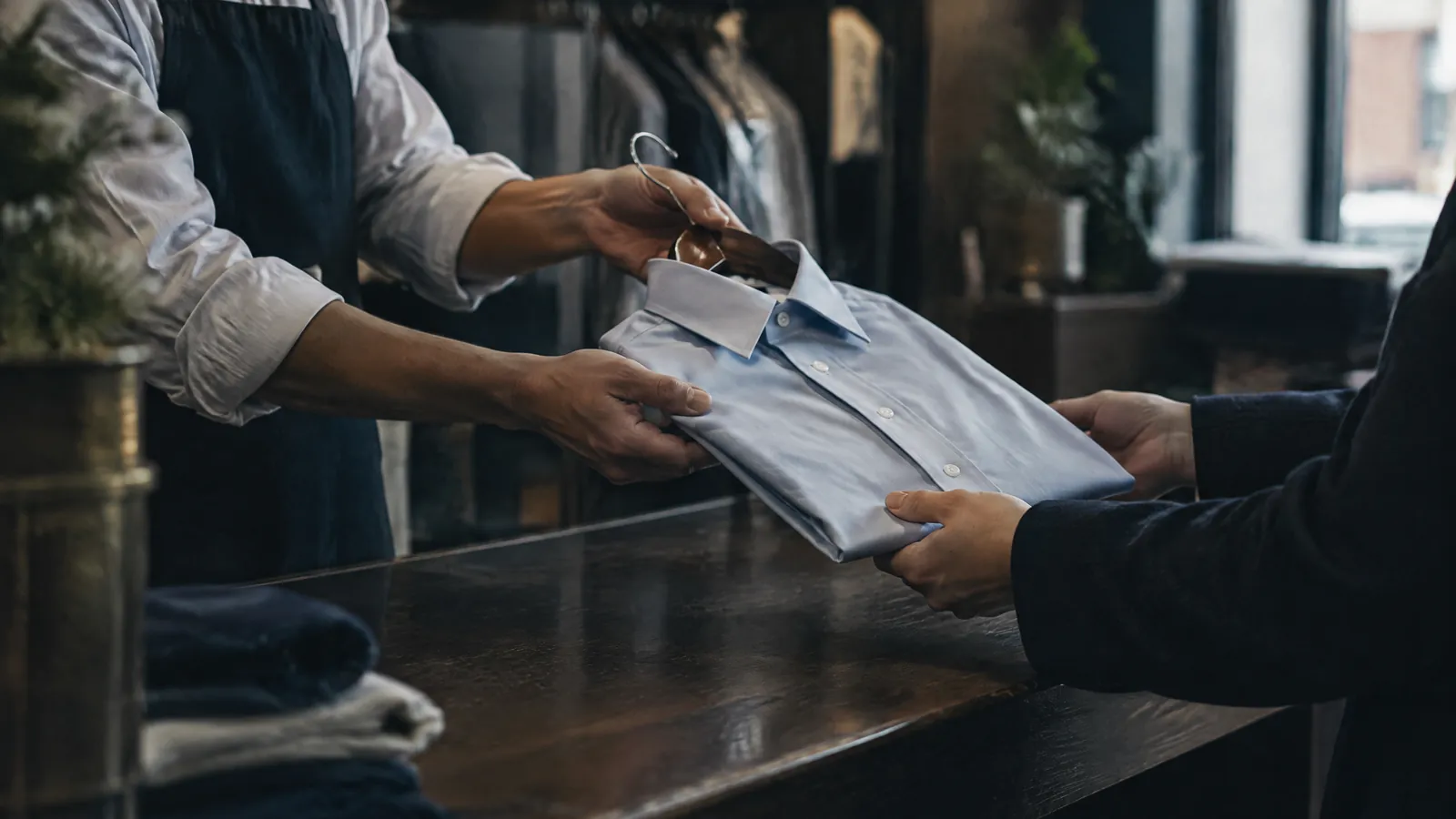 Shop assistant handing a folded shirt across a counter to a customer