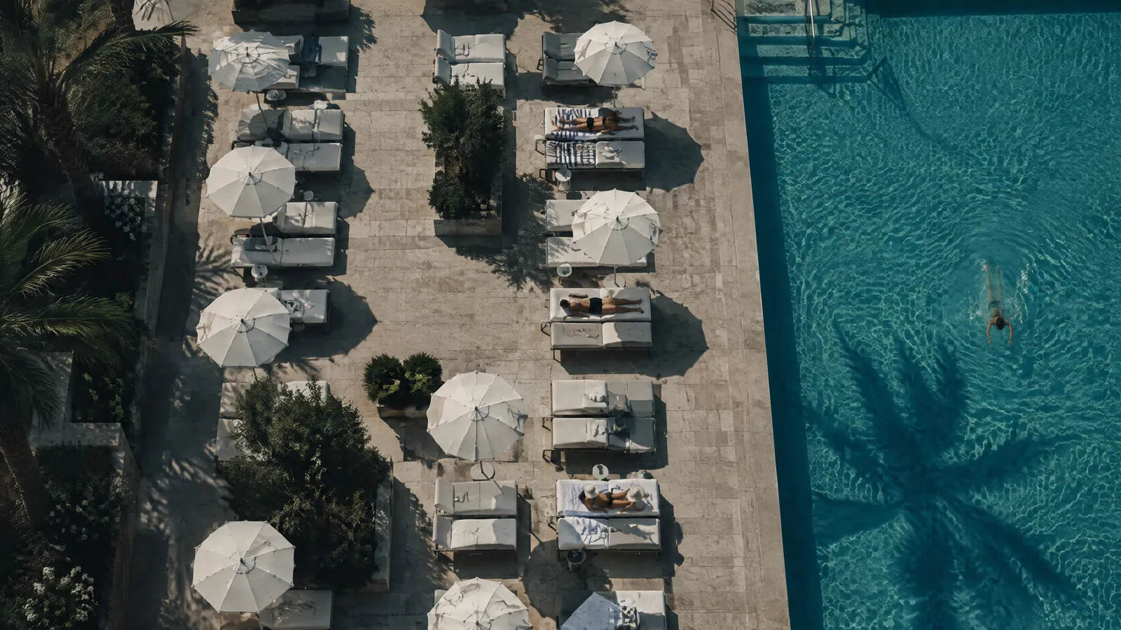 Poolside loungers and white parasols seen from above